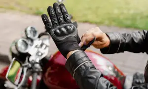 Motocyklista zapina rękawicę z ochraniaczami. Różne rodzaje ochraniaczy zapewniają bezpieczeństwo.