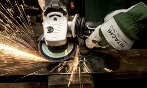 Ręka w rękawicy Hitachi szlifuje metal, tworząc deszcz iskier. To przykład działania siły tarcia statycznego.