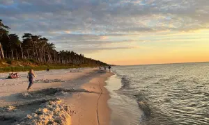 Piękny zachód słońca na plaży w Choczewie. Ludzie spacerują, a morze delikatnie faluje.