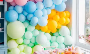 Kolorowa ściana z balonów: pastelowy róż, błękit, żółty i miętowy tworzą radosną oprawę dla świątecznego stołu.