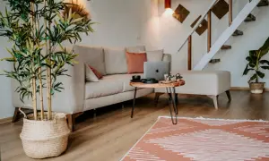Przytulne, małe mieszkanie w stylu boho. Jasna kanapa, bambus w wiklinowym koszu i schody tworzą ciepłą atmosferę.