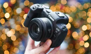 Dłoń trzyma aparat Canon EOS R6 z obiektywem 50 mm f/1.8 STM na tle świątecznych światełek.