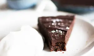 En bit vegansk kladdkaka med en klick vispad grädde, strödd med flingsalt.
