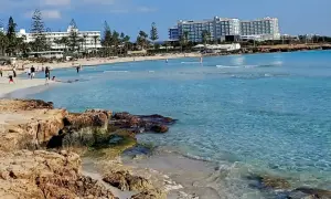 Słoneczny dzień na plaży Ayia Napa. Turkusowa woda, piaszczysty brzeg i hotele w tle.