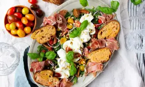 En härlig buffé med appertiff mat: mozzarella, tomater, prosciutto, ruccola och rostat bröd. Perfekt för en somrig förrätt.