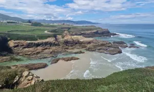 Senderistas disfrutan de las impresionantes rutas senderismo Foz, con acantilados rocosos, playas de arena y el mar azul.