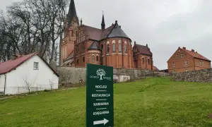 Dom Pielgrzyma w Gietrzwałdzie oferuje noclegi, restaurację, kawiarnię i księgarnię. W tle kościół.