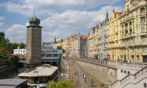 Vue animée de la Vltava, idéale pour visiter Prague en 1 jour. La tour de la Poudrière et les façades colorées des immeubles bordent la promenade.