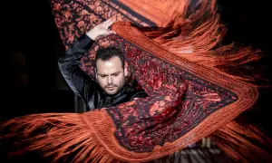 Un bailarín flamenco agita un mantón de Manila de origen oriental, con flecos anaranjados y estampado floral.