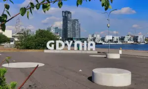 Idealny weekend w Trójmieście zaczyna się od napisu GDYNIA. W tle nowoczesna architektura i żaglowiec.