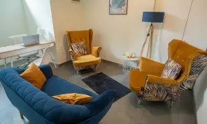 Wnętrze gabinetu psychologicznego z kanapą, fotelami i biurkiem.