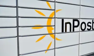 Zbliżenie na białą paczkomat InPost z żółtym logo i czarnym napisem.