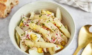 Schüssel mit Spargelsalat mit Ei, Radieschen und Schnittlauch, dazu ein Stück Baguette.