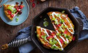 En saftig okonomiyaki i gjutjärnspanna, toppad med gräddfil, salladslök och chili. Ett perfekt recept för en smakrik middag.