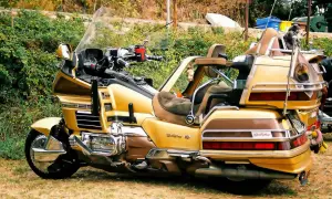 Złoty motocykl turystyczny z dużym bagażnikiem i wygodnymi siedzeniami.