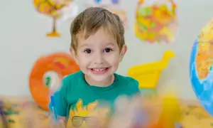 Niño sonriente con camiseta verde, aprendiendo sobre el mundo. Fomenta la autoestima en niños de 6 a 12 años.