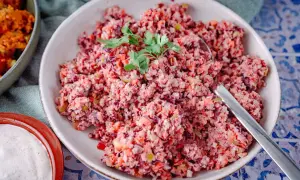 Bunter Karottensalat, frisch zubereitet im Thermomix, garniert mit Petersilie. Daneben eine Schale mit cremiger Sauce.