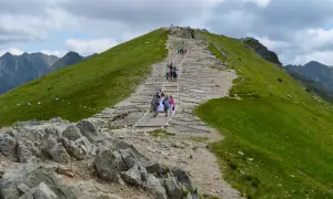 Trasa na Kasprowy Wierch. Grupa turystów, w tym para młoda, wspina się po kamiennych schodach.