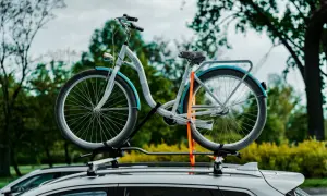 Biały rower z niebieskimi akcentami, zamocowany na dachu samochodu. Czy rower to pojazd mechaniczny? To pytanie zadaje sobie wielu, ale ten jednoślad czeka na podróż.