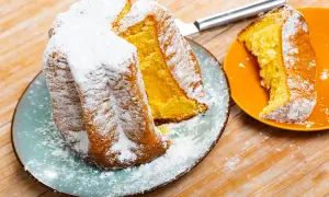 Une brioche italienne pandoro, saupoudrée de sucre glace, est servie sur une assiette bleue. Une part est sur une assiette orange.