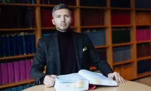 Mężczyzna w garniturze z książkami, przygotowuje się do obrony w sądzie bez adwokata.