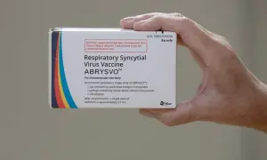 Dłoń trzyma pudełko szczepionki ABRYSVO™ przeciw wirusowi RSV.