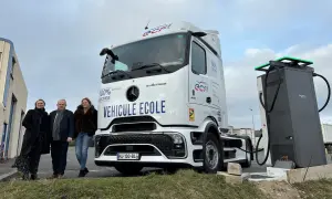 Trois personnes posent devant un camion école 100% électrique, prêt à être rechargé. L'avenir des camions électriques est en marche.