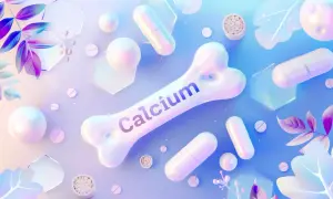 Biała kość z napisem "Calcium", tabletki, kapsułki i ozdobne liście na pastelowym tle.