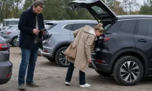 Man med laddkabel vid en begagnad elbil. Kvinna tittar i bagageluckan på en annan elbil.