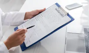 Manos de médico revisan un historial médico en un portapapeles, preparándose para un certificado médico A2.
