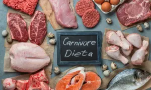 Różnorodne mięsa i ryby, jajka, kości. Tabliczka z napisem "Carnivore Dieta" sugeruje, że to składniki diety mięsożercy.