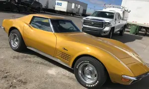 Złoty Chevrolet Corvette Stingray, klasyk wśród amerykańskich samochodów, stoi obok białej ciężarówki.