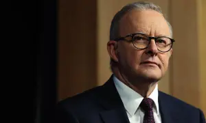Primo piano di Anthony Albanese, uno dei più noti personaggi famosi australiani, con occhiali e abito scuro.