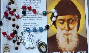 Koronka do św. Charbela, z kolorowymi paciorkami i medalikiem, obok wizerunku świętego. Idealna do odmawiania litanii do św. Charbela 9 dni.