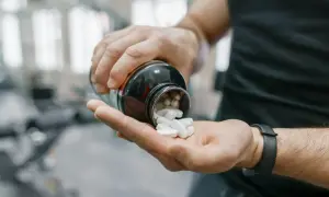 Uomo in palestra versa creatina in polvere nella mano. Ottimizza i tuoi allenamenti: scopri creatina quando assumerla per massimizzare i risultati.