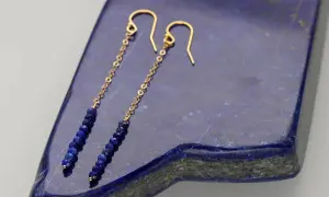 Eleganckie kolczyki z lapis lazuli na złotym łańcuszku, zakończone zapięciem bigiel.
