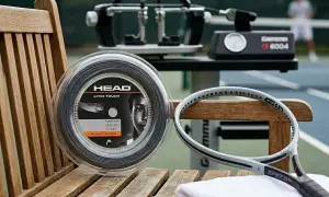 Bobina di corde tennis ibride HEAD Lynx Touch, racchetta e incordatrice su un campo da tennis.