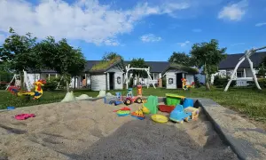 Piaskownica pełna zabawek, huśtawki i kolorowy kogut – to idealne rusinowo atrakcje dla dzieci.