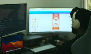 Programista w słuchawkach pracuje nad kodem w C++, widoczny jest ekran z kodem i interfejsem.
