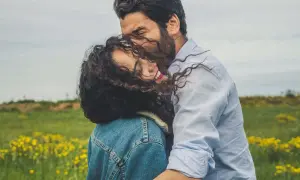 Un abbraccio intenso in un prato fiorito, un momento di pura comunicazione di coppia, dove sguardi e gesti parlano più delle parole.