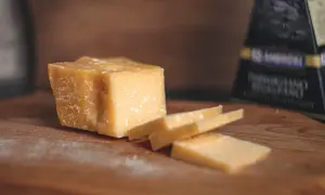 Kawałek parmezanu, idealny na przekąskę w ciąży, pokrojony na desce.