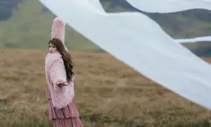Sylwia Grzeszczak w różowym futrze i sukience, jakby unosiła się na wietrze, niczym latawce.