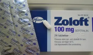 Opakowanie leku Zoloft 100 mg z sertraliną i blister z tabletkami.