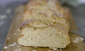 Ein frisch gebackener Hefezopf, aufgeschnitten auf einem Holzbrett, mit Mandelblättchen bestreut. Ein leckeres Rezept für den Sonntagsbrunch.