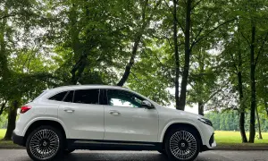 Biały Mercedes EQA stoi na tle zielonego, leśnego krajobrazu.
