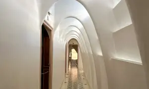 Korytarz z białym, falującym sklepieniem łukowym i ozdobną posadzką.