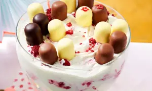 Schokoladen- und weiße Schaumküsse auf einer cremigen Nachspeise mit Himbeeren in einer Glasschüssel.