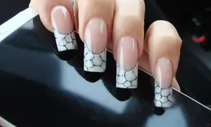 Manucure française avec un motif écaille de tortue sur les ongles, posée sur un écran noir.