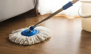 Mop z mikrofibry na drewnianej podłodze, gotowy do czyszczenia. Dowiedz się, czym nabłyszczyć panele, by lśniły jak nowe.