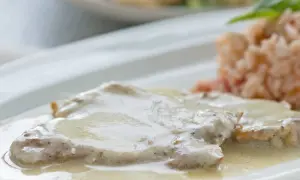 Zartes Putenschnitzel mit cremiger Rahmsauce, serviert mit einer Beilage aus Reis. Ein köstliches Gericht.